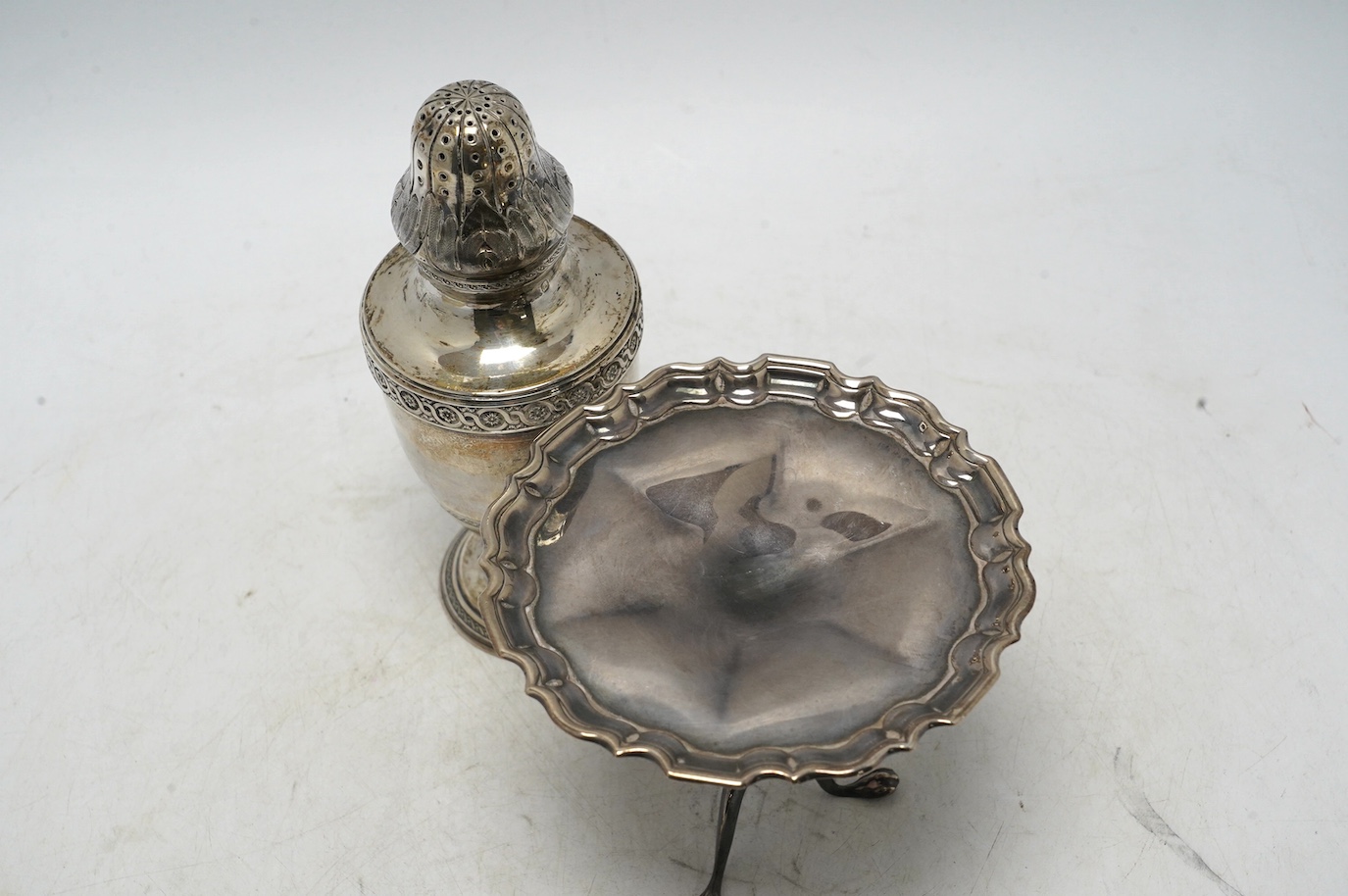 An Edwardian silver miniature model of a tripod table with piecrust border, Goldsmiths & Silversmiths Co Ltd, Sheffield, 1908, diameter 11.1cm, together with a French 950 standard white metal sugar caster, 7.3oz. Conditi